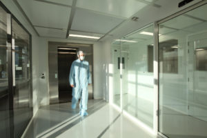 homme en combinaison stérile qui marche dans un couloir de salle blanche par Rosin Entreprise