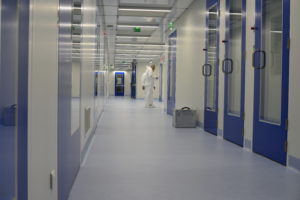 hommes dans un couloirs de salles blanches avec des portes bleues par Rosin Entreprise