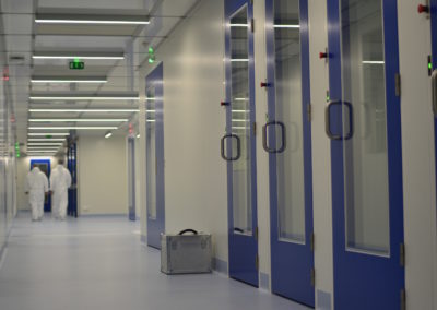 hommes dans un couloirs de salles blanches avec des portes bleues par Rosin Entreprise