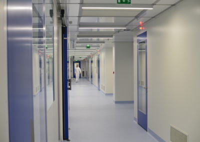 homme dans un couloirs de salles blanches avec des portes bleues par Rosin Entreprise
