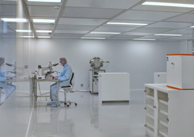 homme en combinaison stérile dans une salle propre devant un microscope par Rosin Entreprise